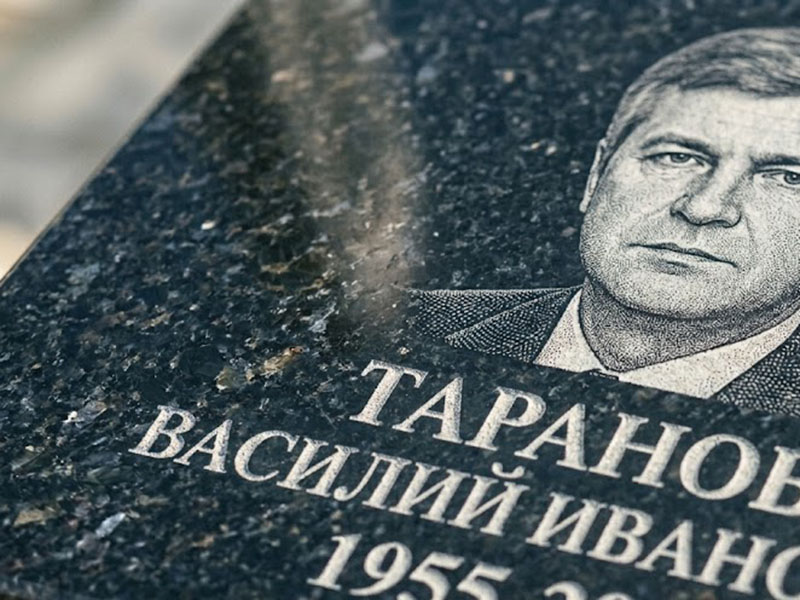 Гравировка портрета и ФИО на темном гранитном памятнике крупным планом.
